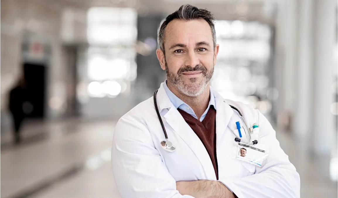 A doctor in a white coat standing in a clinic corridor
